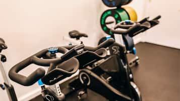 A stationary bike with handlebars, a control panel, and a weight stack in the background.