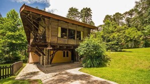 A wooden house with a balcony, stone pathway, and lush greenery. - Paraíso na Montanha House Boutique (Campos do Jordão)