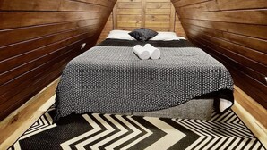 A narrow, wooden-paneled room with a bed, pillows, and a patterned rug. - Paraíso na Montanha House Boutique (Campos do Jordão)