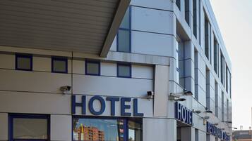 A hotel with a modern facade, large glass windows, and a prominent "HOTEL" sign.