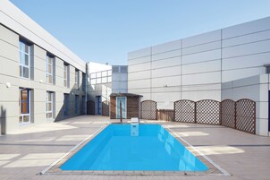 A modern building with a swimming pool, large windows, and a covered outdoor area.