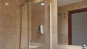 A modern bathroom with a glass-enclosed shower, a white bathtub, and a pedestal sink.