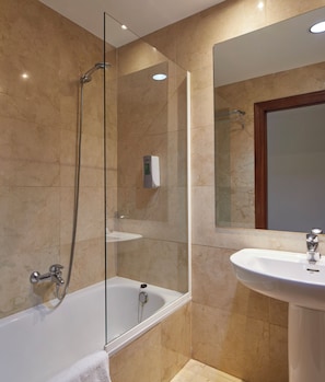 Une salle de bain moderne avec une douche à parois de verre, une baignoire blanche et un lavabo sur pied.