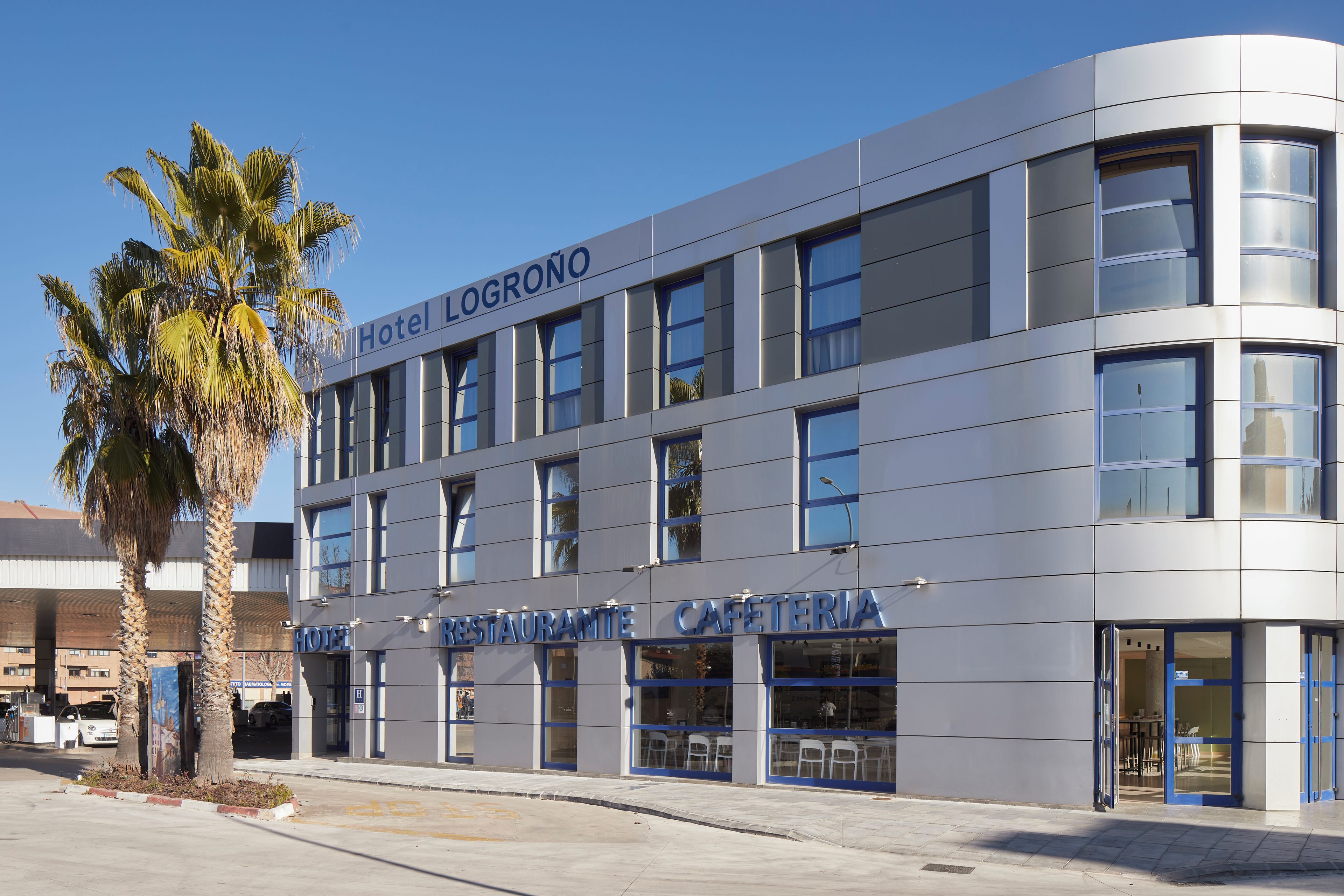 Um edifício de hotel moderno com uma placa indicando 'Hotel Logroño Restaurante Cafeteria'.