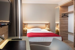 Une chambre d’hôtel avec un lit, des tables de chevet, une télévision et un bureau.