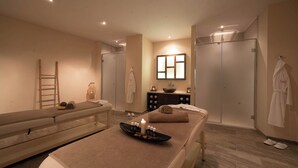 Un cuarto de spa con una camilla de masaje, un lavamanos pequeño y un espejo.