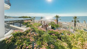 A balcony with a view of the sea, a beach with umbrellas, and a building with solar panels. - Sentido Marea (Varna)