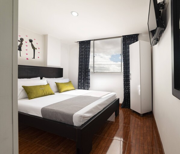 Una habitación de hotel moderna con una cama, un televisor de pantalla plana, un ventanal con cortinas y una pared decorada con un corazón.