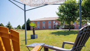 Eine Terrasse mit Sitzgelegenheiten im Freien, einer Palme und einem Gebäude im Hintergrund.