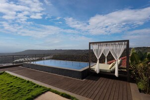 Una piscina en la azotea con terraza de madera, un área de estar cubierta con techo y vistas al paisaje.