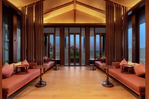 A room with a wooden ceiling, large sliding doors, and a seating area with tables.
