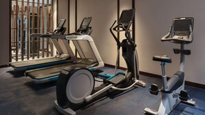 Un gimnasio con cintas de correr, elíptica y bicicleta estática.