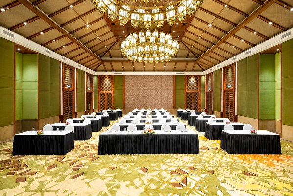 A conference room with multiple tables, a chandelier, and a patterned carpet.