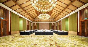 A conference room with a high ceiling, chandeliers, and a patterned carpet.