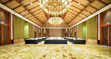 Un salón de conferencias con techo alto, candelabros y alfombra estampada.