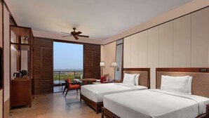 Habitación de hotel con dos camas, balcón, ventilador de techo y vistas al exterior.
