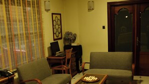 Un salon comprenant deux canapés, une table basse, un bureau avec un ordinateur et une bibliothèque.