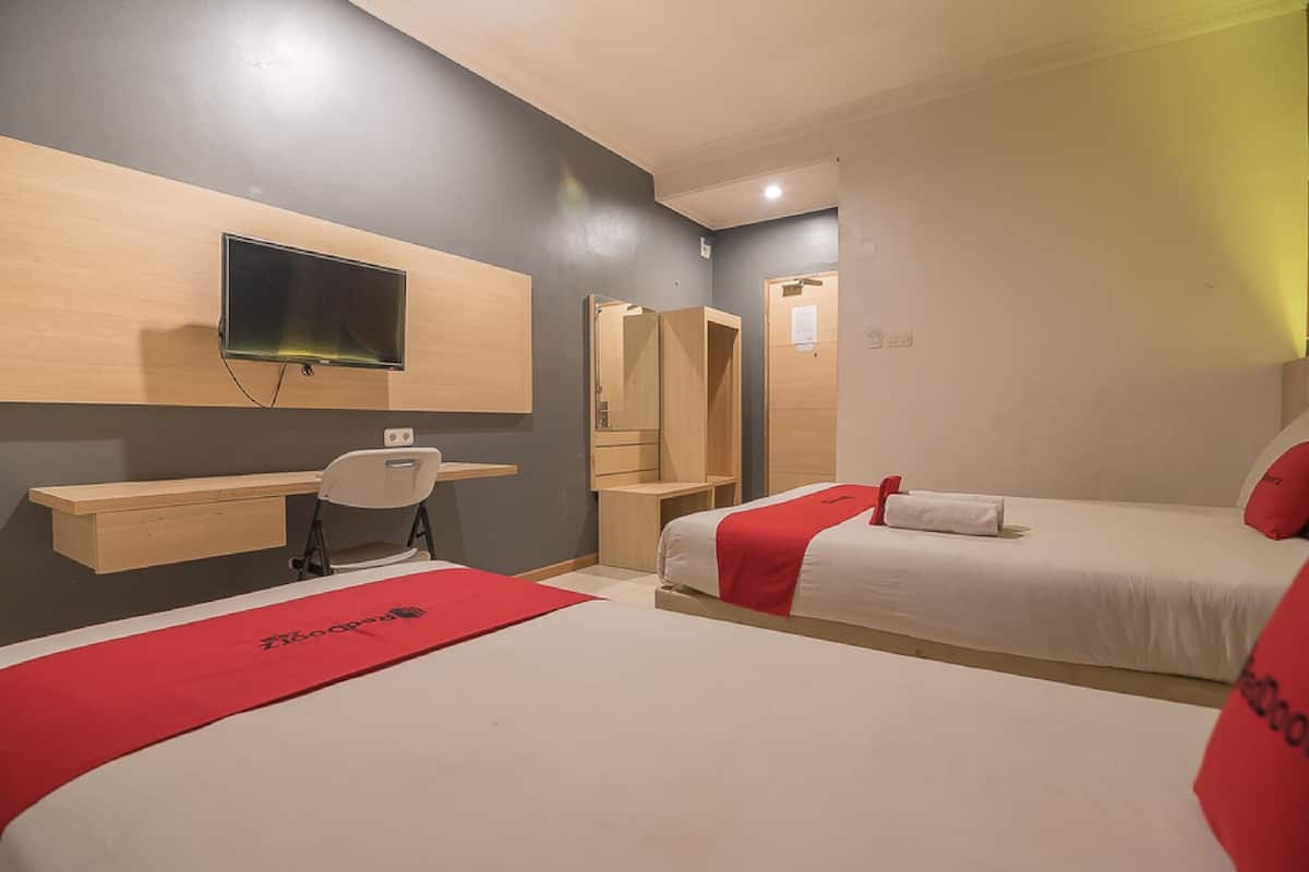 A hotel room with two beds, a desk, a chair, a TV, and a mirror.