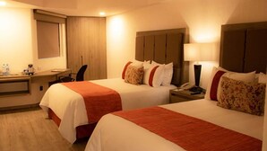 Ein Hotelzimmer mit zwei Betten, einem Schreibtisch und einem Stuhl.