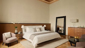 Een hotelkamer met een groot bed, een zithoek met een stoel, een klein tafeltje en een kast.