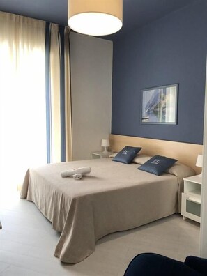 A hotel room with a large bed, a bedside table with a lamp, and a painting on the wall. - Hotel Doria Lavagna (Lavagna)