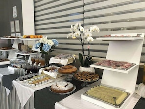 A buffet setup with various food items and a decorative orchid arrangement. - Hotel Doria Lavagna (Lavagna)