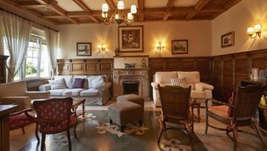 A traditional room with a fireplace, wooden paneling, and classic furniture including a sofa, chairs, and ottoman. - Hotel y Casona El Carmen (Carreno)