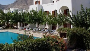 A hotel with white architecture, a pool, and a mountain in the background. - Areti Hotel (Santorini)