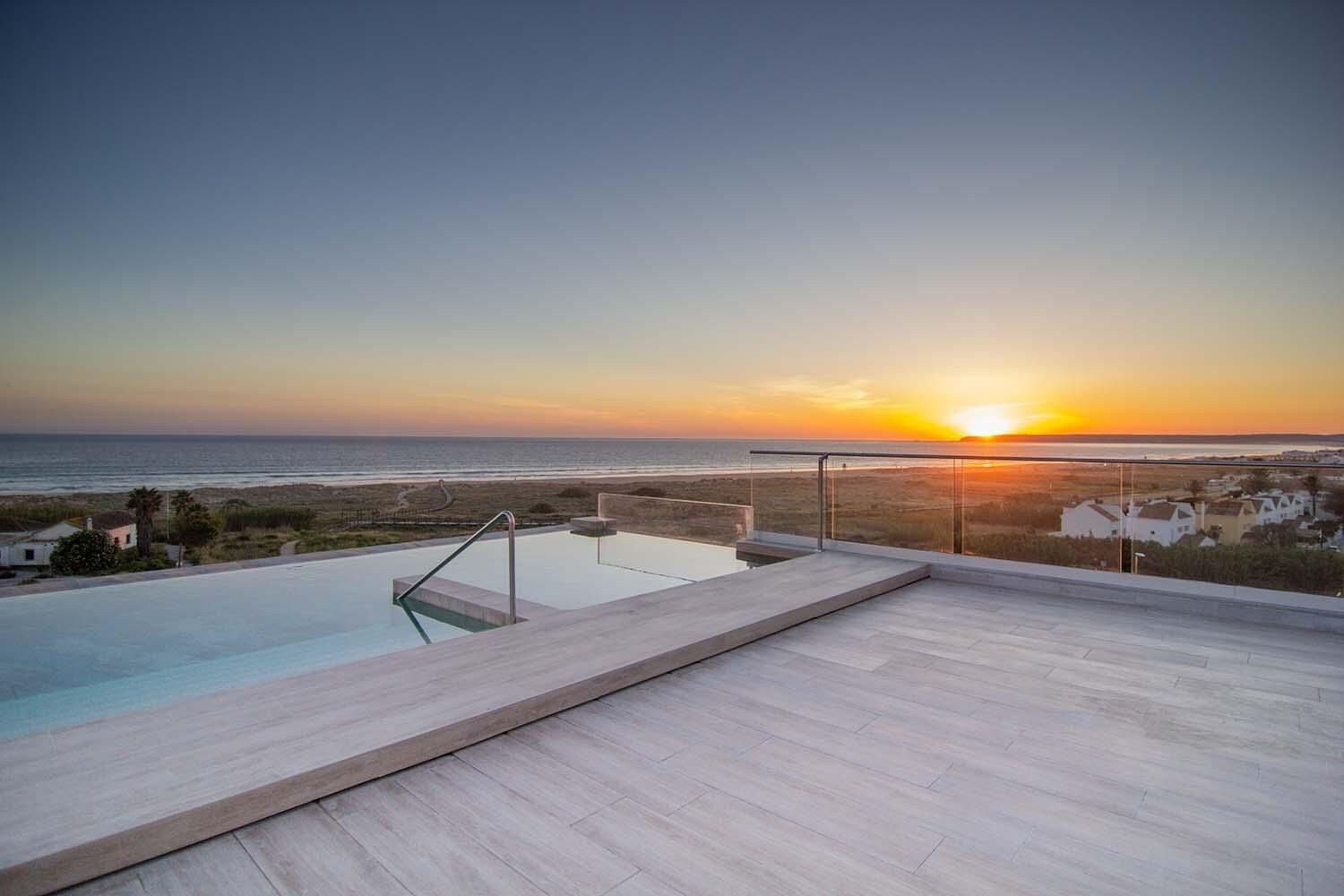 Una piscina infinita en la azotea con vistas a la puesta de sol sobre el océano.
