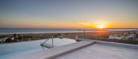 Ein Infinity-Pool auf dem Dach mit Blick auf den Sonnenuntergang über dem Meer.