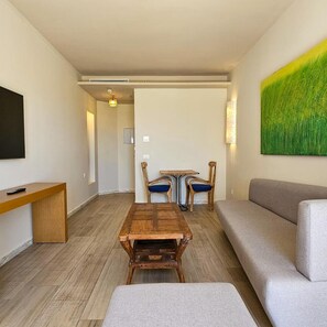 A modern living room with a wooden coffee table, a grey sofa, and a television on the left.