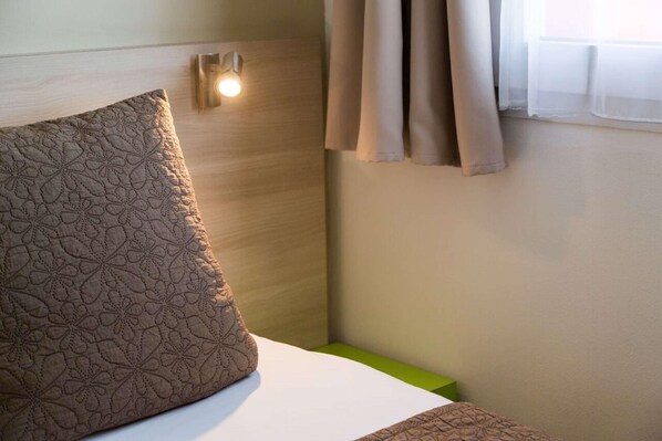 A hotel room with a bed, a nightstand, a bedside lamp, and a window with curtains. - Sure Hotel by Best Western Nantes Saint-herblain (Saint-Herblain)