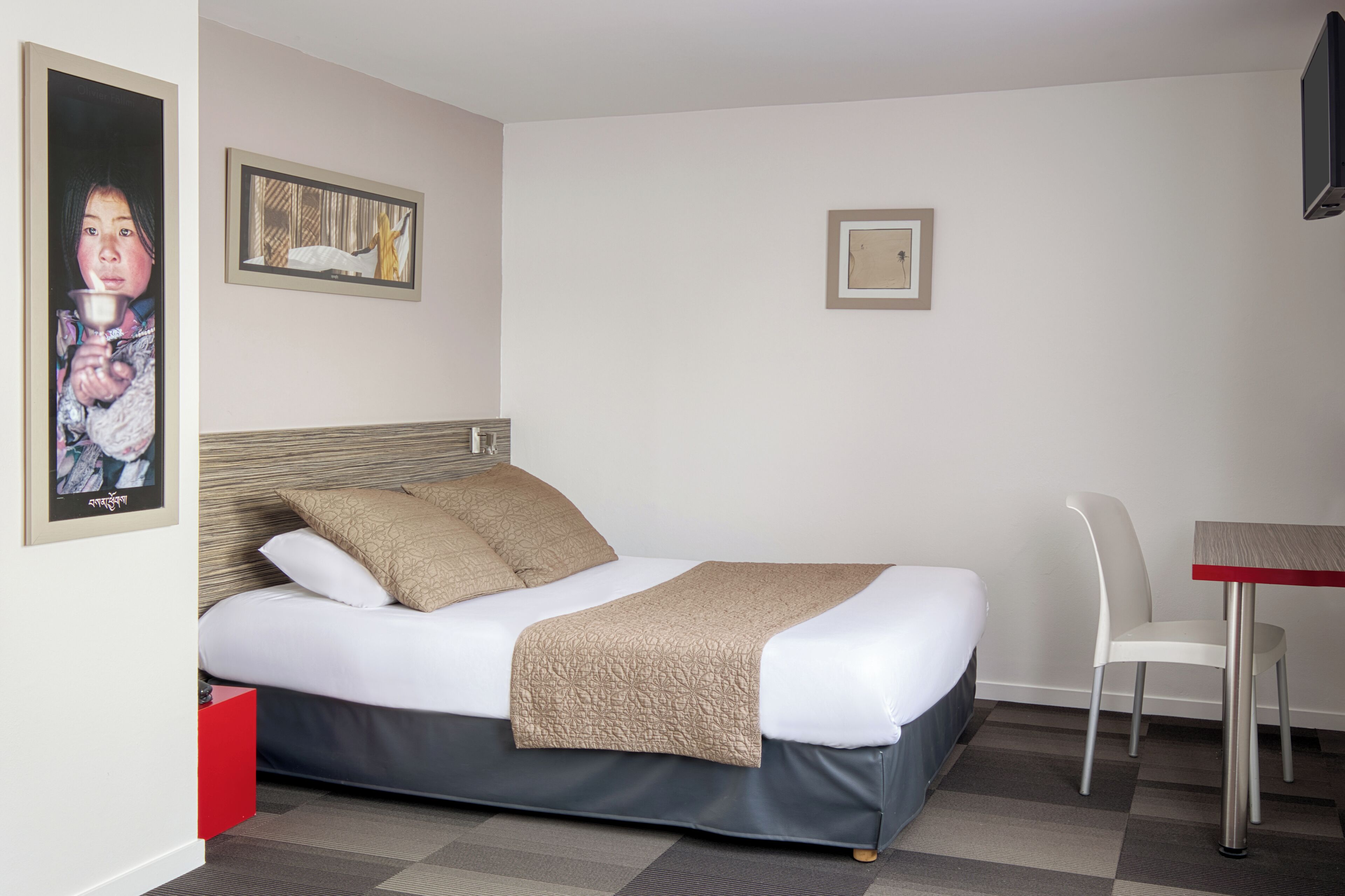 A hotel room with a bed, a desk, and a chair.