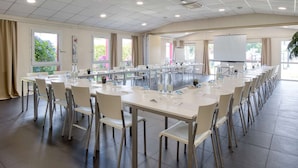 Una sala conferenze con diversi tavoli e sedie, ampie finestre e una lavagna.