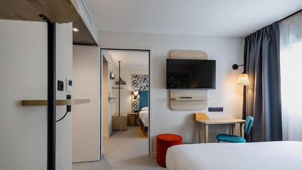 Una camera d'albergo con un letto, una televisione, una scrivania e una sedia.
