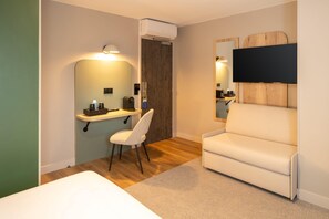 A modern hotel room with a bed, a desk with a chair, a TV mounted on a wooden headboard, and an air conditioning unit. - Sure Hotel by Best Western Tours Sud (Chambray-les-Tours)