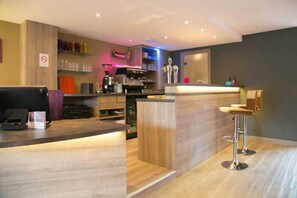 Eine moderne Bar mit Holztresen, Barhocker und einer Kaffeemaschine.