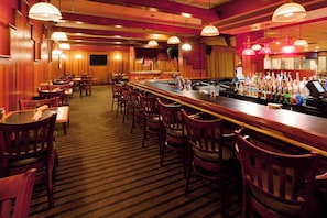 A bar area with wooden chairs, a bar counter, and a variety of bottles. - Holiday Inn Harrisburg - Hershey Area, I-81 by IHG (Grantville)