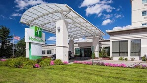 Ένα ξενοδοχείο Holiday Inn με σκεπαστή είσοδο, μια μεγάλη επιγραφή και έναν καλά περιποιημένο κήπο.