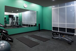 A gym with exercise equipment, a large mirror, and a bench.