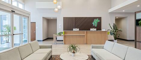 Un hall d’entrée moderne avec des canapés, un comptoir d’accueil et une grande fenêtre.