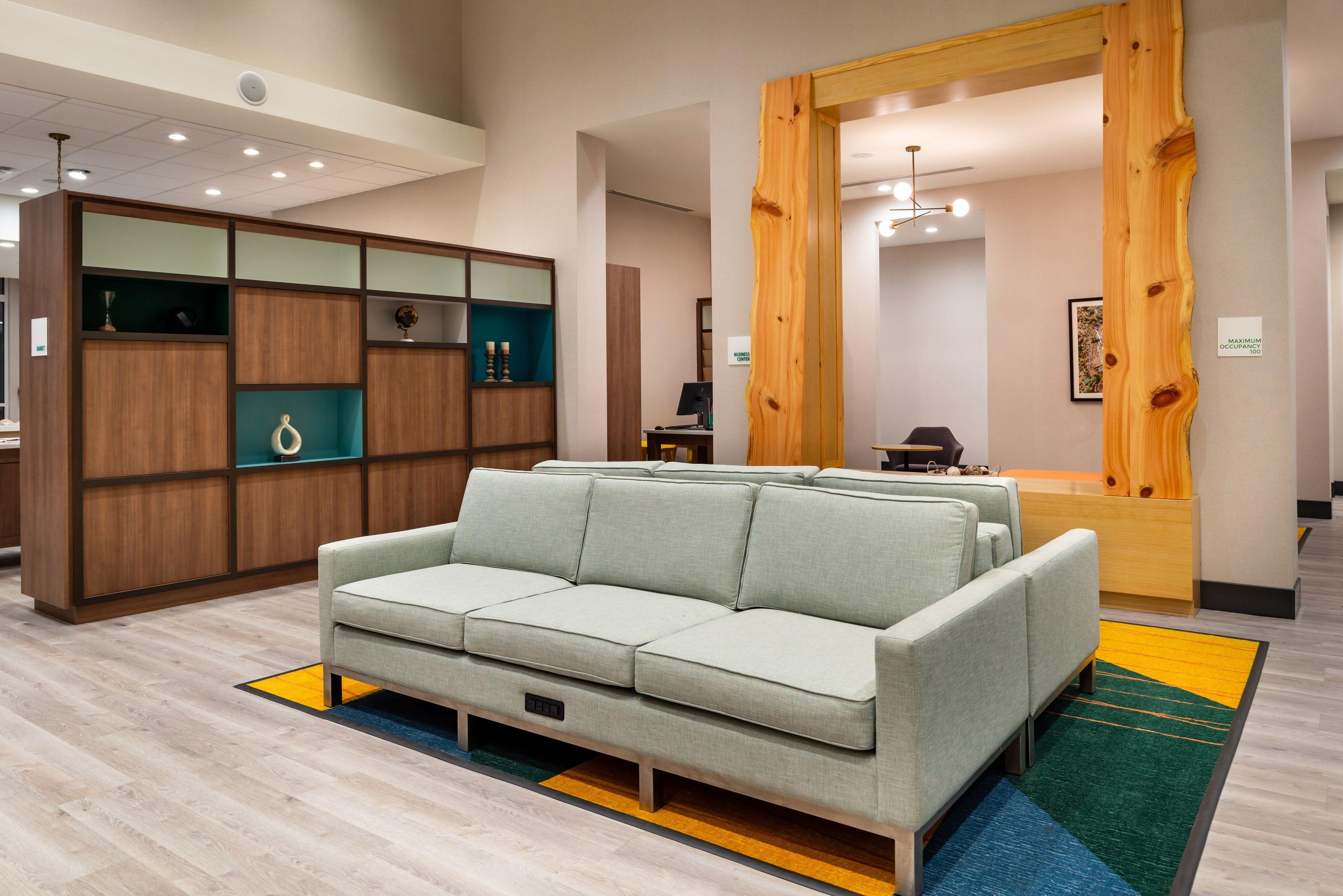 A modern hotel lobby with a light-colored sofa, wooden display cabinets, and a large mirror.