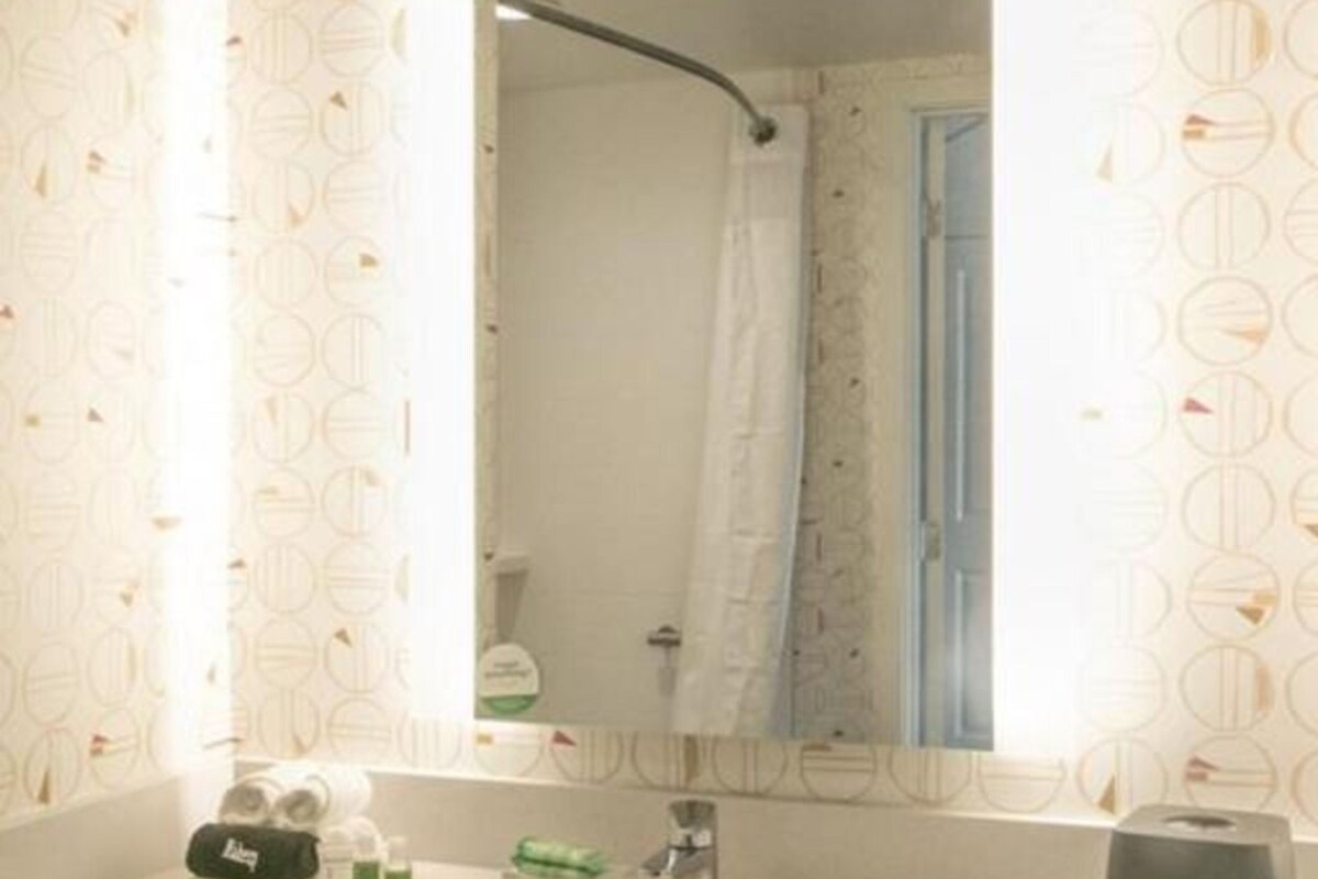 A bathroom with a white sink, a mirror, and a shower curtain.