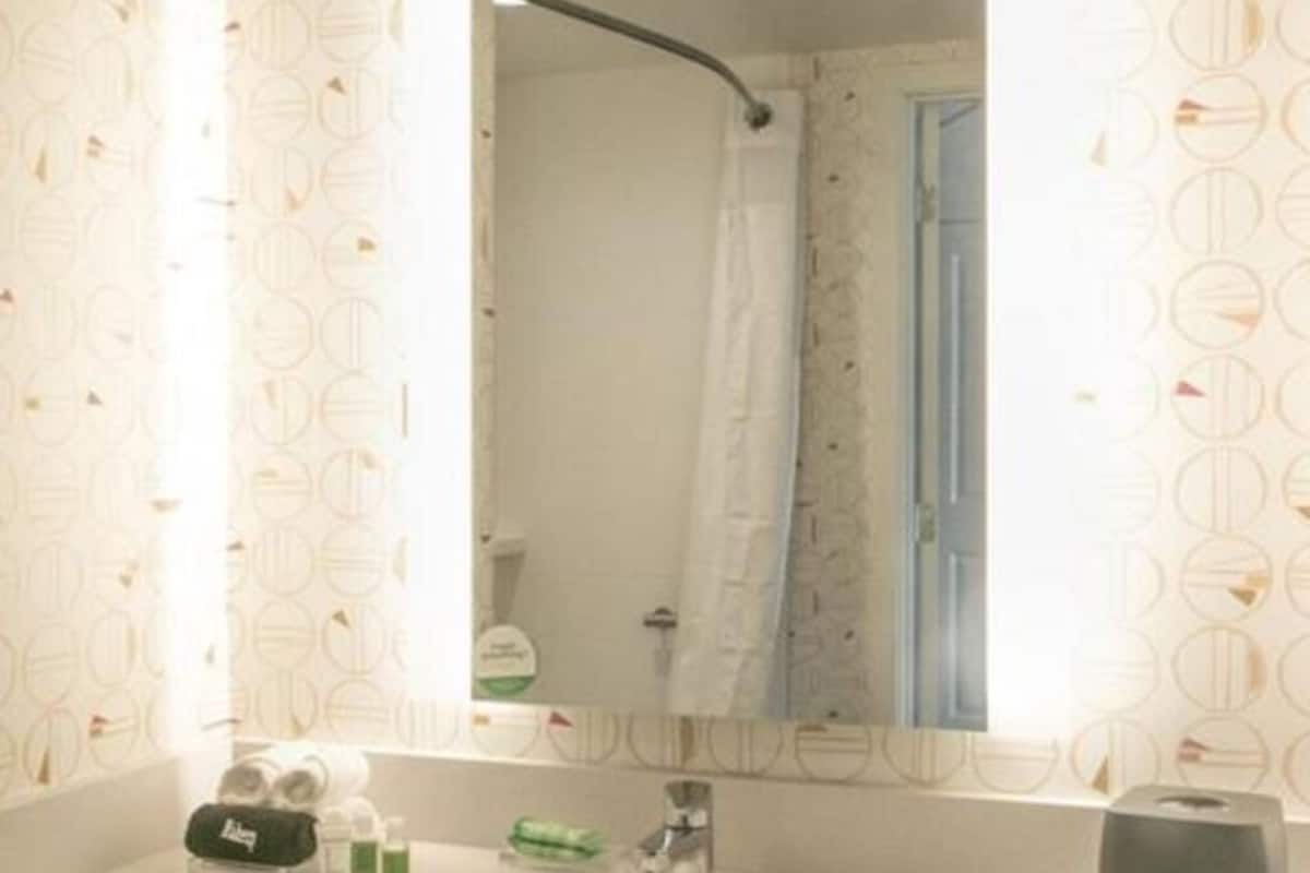 Un baño con lavamanos blanco, un espejo y cortina de ducha.