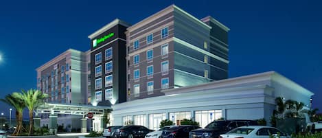 A hotel with a modern design, a parking lot, and a stop sign.