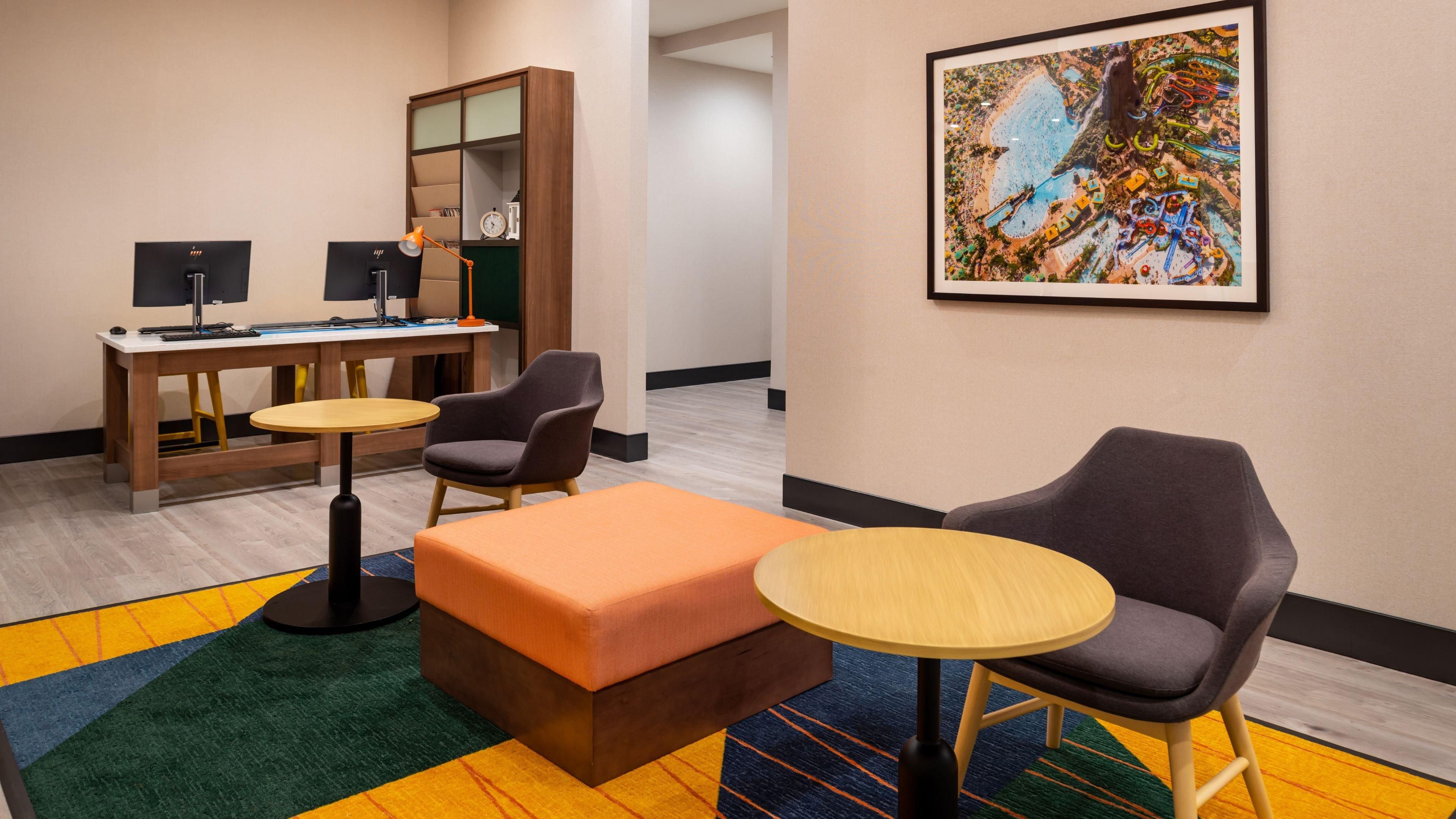 Une chambre d’hôtel équipée d’un bureau, de deux chaises, d’une petite table, d’un canapé, d’un tapis et d’un tableau accroché au mur.