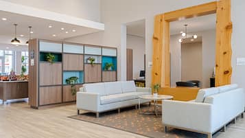 A modern interior with a light-colored sofa, a wooden reception desk, and a patterned rug.