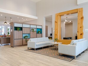 A modern interior with a light-colored sofa, a wooden reception desk, and a patterned rug.