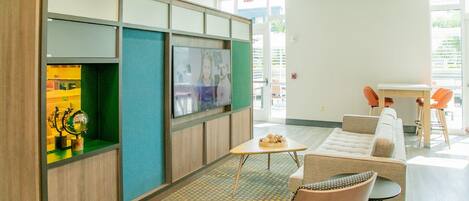 Un hall con mostrador de recepción, zona de estar y una pantalla de televisión.