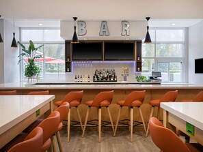 A bar area with a countertop, bar stools, a TV, and a sign that reads 'BAR'.